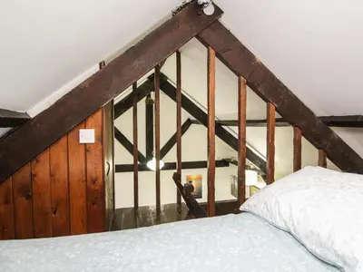 a bedroom with a bed and a wooden wall at Coachman's in Forrabury