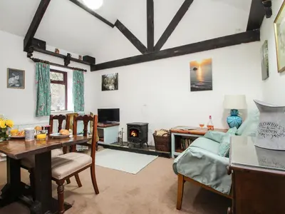 a living room with a table and a fireplace at Coachman's in Forrabury