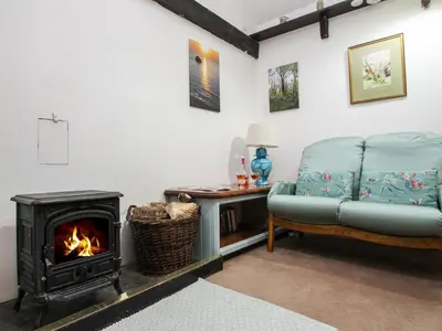 a living room with a fireplace and a couch at Coachman's in Forrabury