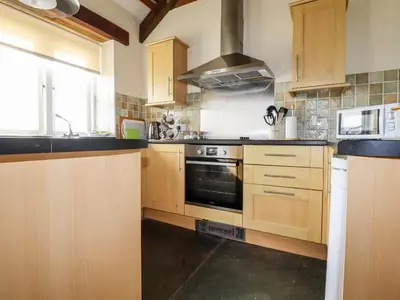 a kitchen with wooden cabinets and a stove top oven at Wheal Kitty in Newlyn East