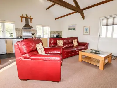 a living room with a red leather couch and a table at Wheal Rose in Newlyn East