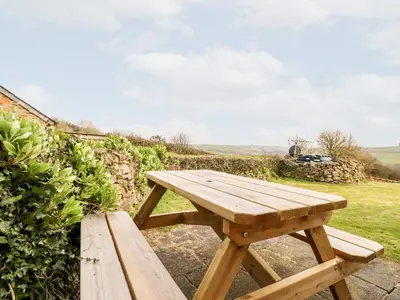 a wooden picnic table sitting in a field at Wheal Rose in Newlyn East