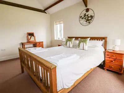a bedroom with a large wooden bed with white sheets at Wheal Rose in Newlyn East