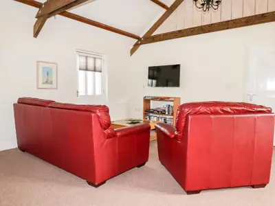 two red chairs in a living room with a table at Wheal Rose in Newlyn East