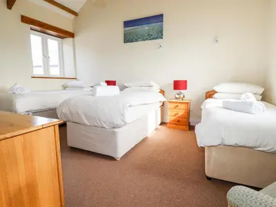 a room with three beds and a desk and a table at Wheal Hart in Newlyn East
