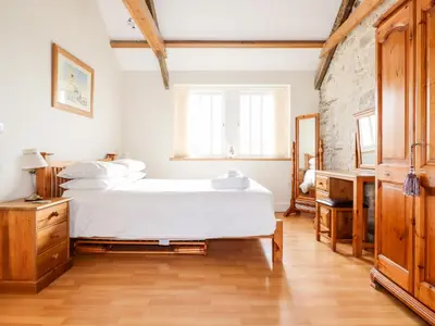 a bedroom with a white bed and a brick wall at Wheal Hart in Newlyn East