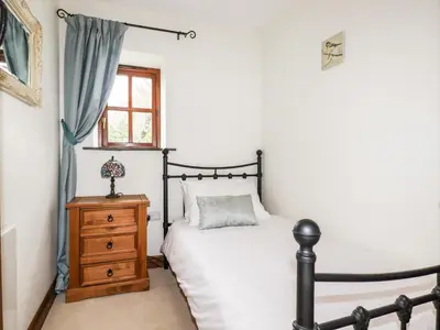 a bedroom with a bed and a dresser and a window at Brocks Barn in Lanlivery