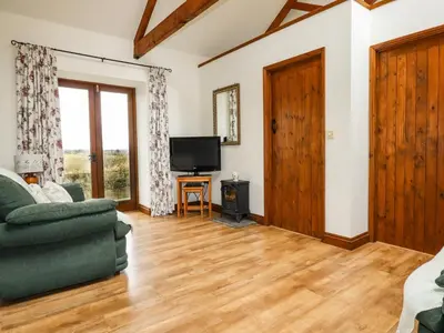 a living room with a green couch and a television at Brocks Barn in Lanlivery