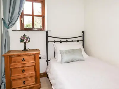 a bedroom with a bed and a dresser and a window at Brocks Barn in Lanlivery