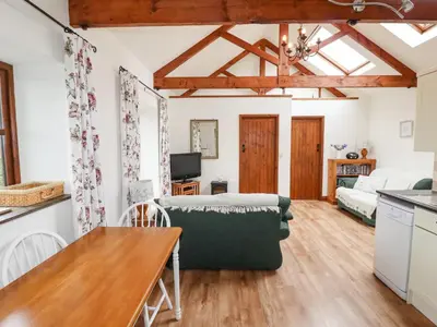 a kitchen and living room with a couch and a table at Brocks Barn in Lanlivery