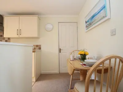 a small kitchen with a table and a table and chairs at An Kres in Mevagissey