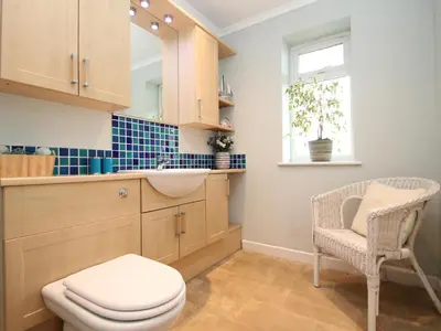 a bathroom with a toilet and a sink and a chair at An Kres in Mevagissey