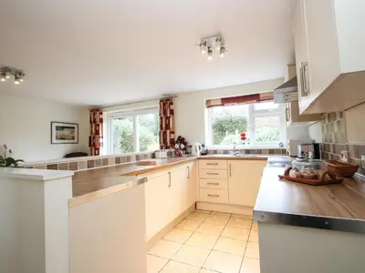 a large kitchen with white cabinets and counters at An Kres in Mevagissey