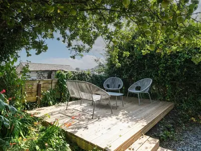 two chairs sitting on a wooden deck under a tree at 5 Bodmin Hill in Lostwithiel