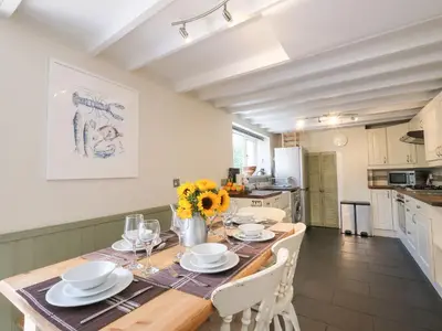 a dining room with a table and chairs and a kitchen at 5 Bodmin Hill in Lostwithiel