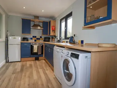 a kitchen with blue cabinets and a washing machine at The Station Flat in Newlyn East