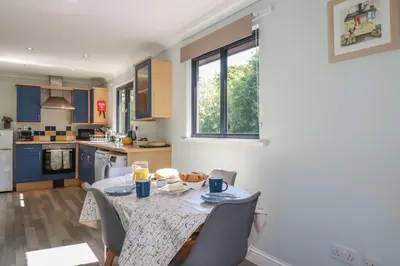 a kitchen with a table and chairs and a kitchen with blue cabinets at The Station Flat in Newlyn East