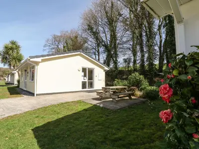 a white building with a picnic table in a yard at 3 Rosecraddoc Lodge in Saint Cleer