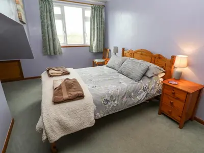 a bedroom with a bed and a table with a night stand at Trelydarth in St. Agnes