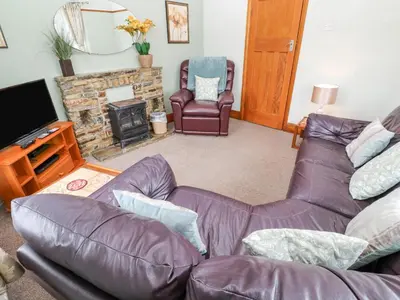 a living room with a leather couch and a fireplace at Trelydarth in St. Agnes