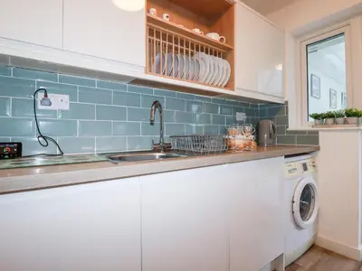 a kitchen with a sink and a washing machine at Harlyn in Mevagissey