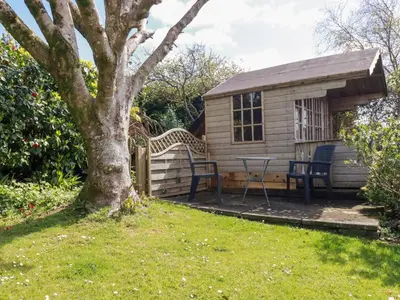 a small cabin with a table and a tree at Harlyn in Mevagissey