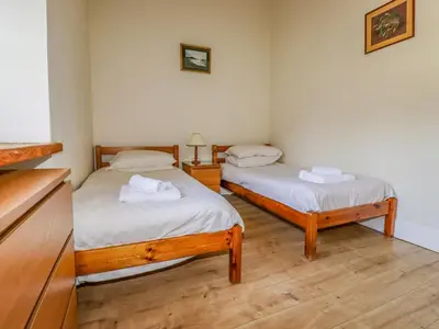 two twin beds in a room with wooden floors at Wheal Honey in Newlyn East