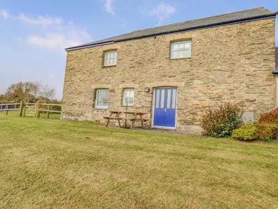 a brick house with a blue door and a yard at Wheal Honey in Newlyn East