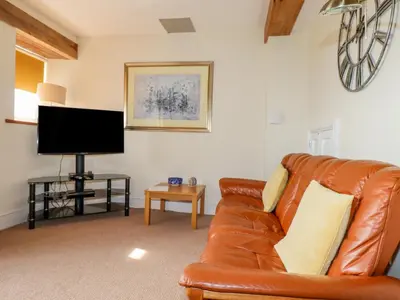 a living room with a brown leather couch and a flat screen tv at Wheal Honey in Newlyn East