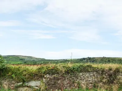 a stone wall in a field with a cloudy sky at The Annexe, Laburnum in Bugle
