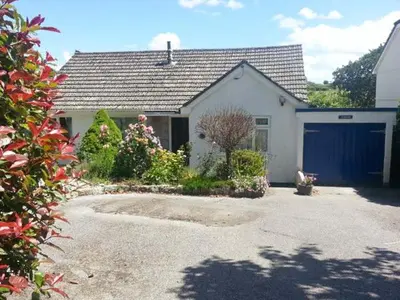 a small white house with a blue garage at Joylands in Budock Water