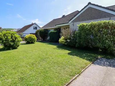 a house with a yard with green grass and bushes at Summerfield Cottage in Gorran Haven