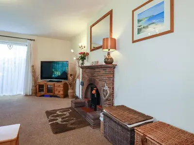 a living room with a fireplace and a television at Summerfield Cottage in Gorran Haven
