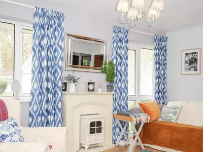 a living room with blue and white curtains and a fireplace at No 1 The Heathers in Saint Cleer