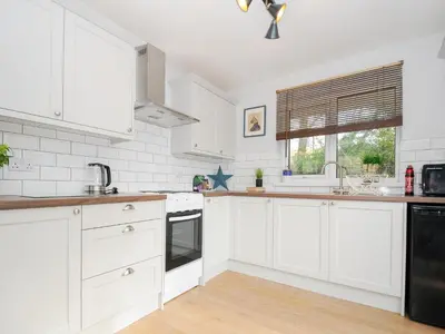 a white kitchen with white cabinets and a window at No 1 The Heathers in Saint Cleer