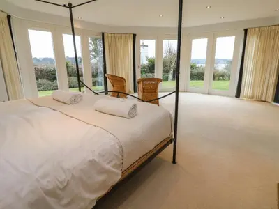 a bedroom with a large bed and windows at Penarvon House in Helford