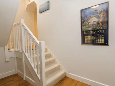 a white staircase with a poster on the wall at Penarvon House in Helford