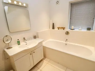 a bathroom with a sink and a tub and a mirror at Penarvon House in Helford