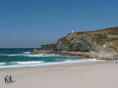 a group of people standing on a beach near the ocean at Tidewood in Polzeath