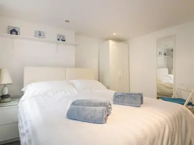 a bedroom with a white bed with towels on it at The Blue House in Tintagel