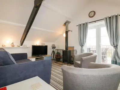 a living room with a couch and chairs and a tv at The Blue House in Tintagel