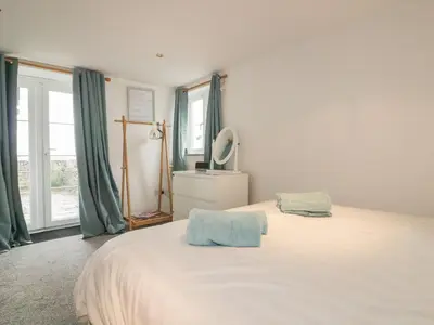 a bedroom with a large white bed with green curtains at The Blue House in Tintagel