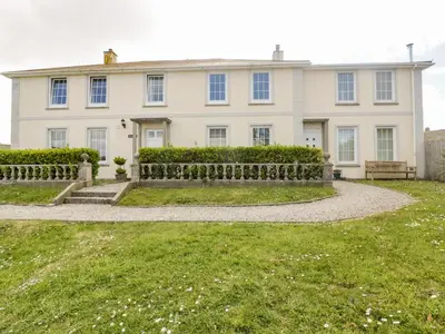 a white house with a fence in front of it at Tremanners in St. Agnes