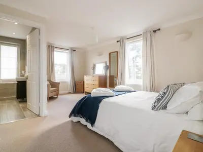 a bedroom with a large white bed and windows at Tremanners in St. Agnes