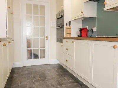 a kitchen with white cabinets and a tile floor at Tremanners in St. Agnes