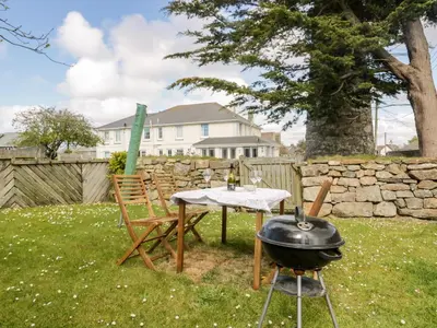a grill and a table and chair in a yard at Tremanners in St. Agnes