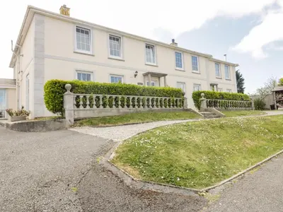 a white house with a fence in front of it at Tremanners in St. Agnes