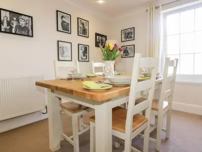a dining room with a wooden table and white chairs at Tremanners in St. Agnes