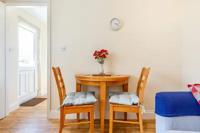 a table with two chairs and a vase with flowers at 19 Cormorant Drive The Annexe in St Austell