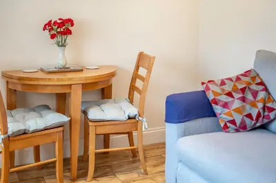 a table with two chairs and a table with a vase of flowers at 19 Cormorant Drive The Annexe in St Austell